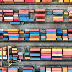 Färgglada containrar staplade på en hamnplan, en symbol för internationell logistik. Chalmers forskar om effektivitet i globala flöden.