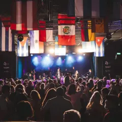 En stor publik njuter av en konsert i Uppsala, med flaggor från olika länder som hänger från taket.