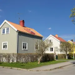 Rad av charmiga trähus i olika färger, med orange tak och gröna fasader. En dröm om ett hem med rimlig belåningsgrad.