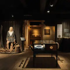 I en vikingamuseum står en vaxdocka som en viking. Utställningen visar föremål och information om vikingatiden.