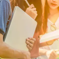 Tre studenter diskuterar sina frågor om Sverige med böcker och laptop.