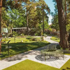 En person spelar minigolf i Aspudden, omgiven av grönska och träd. En vacker sommardag för en runda minigolf.