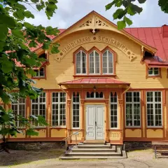 Gult trähus med röda detaljer, "Slöjdlärare Seminarium" text. Perfekt för en byggnadsvård kurs distans.