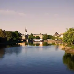 Vacker vy över Klarälven i Karlstad med stadens silhuett, kyrktorn och grönska. Perfekt för gratis aktiviteter Karlstad.