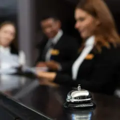 Receptionister i utbildning, redo att hjälpa till. En klocka på disken signalerar service.