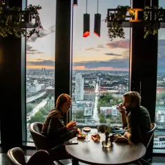 Par som njuter av solnedgången över staden från en takbar. En avkopplande aktivitet bland alla **things to do in Lund**.