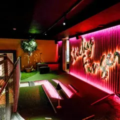 En neonupplyst minigolf bar med en väggtext som säger "Lucky Fun".