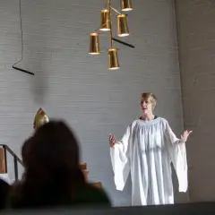 En person i vit alba talar under en diakon utbildning.
