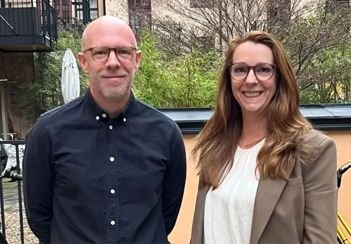 Två leende personer, en man och en kvinna, står utomhus. Kanske är de kollegor som diskuterar vinnova lediga jobb.