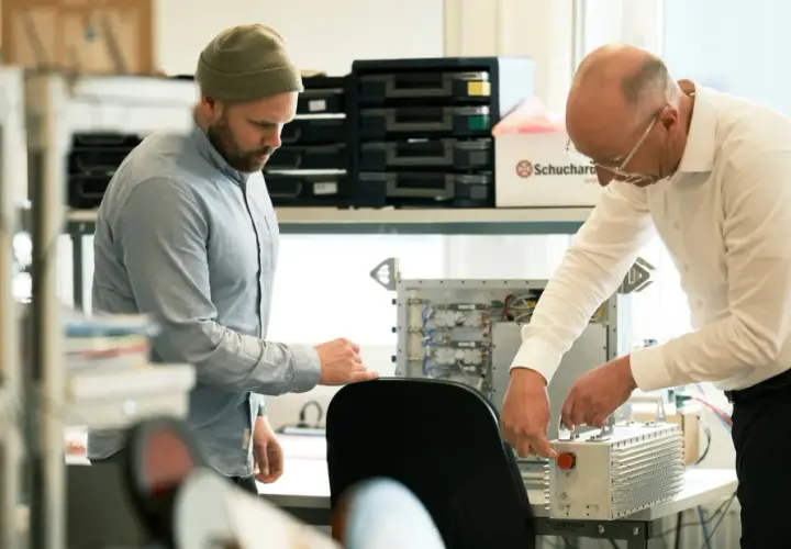 Två män arbetar med elektronik. En creative director ser på när en kollega kopplar ihop komponenter.