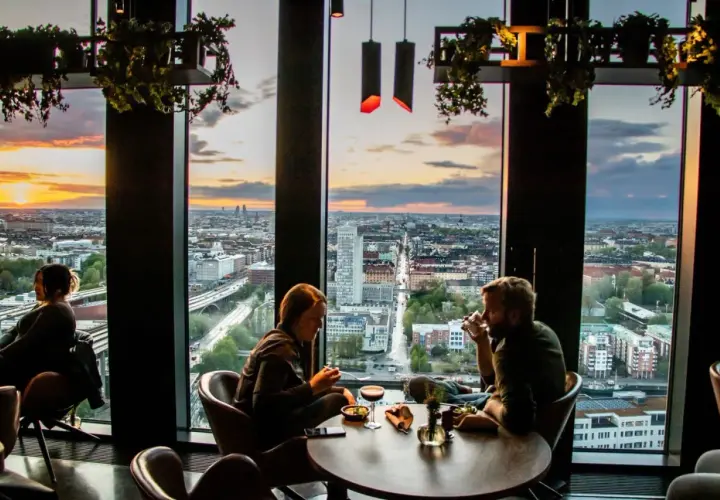 Par som njuter av solnedgången över staden från en takbar. En avkopplande aktivitet bland alla **things to do in Lund**.