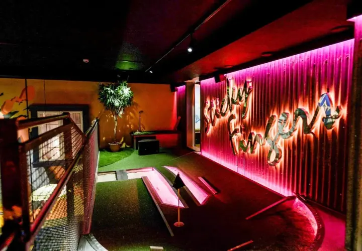 En neonupplyst minigolf bar med en väggtext som säger "Lucky Fun".