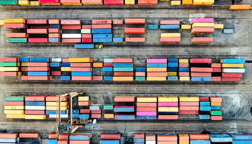 Färgglada containrar staplade på en hamnplan, en symbol för internationell logistik. Chalmers forskar om effektivitet i globala flöden.
