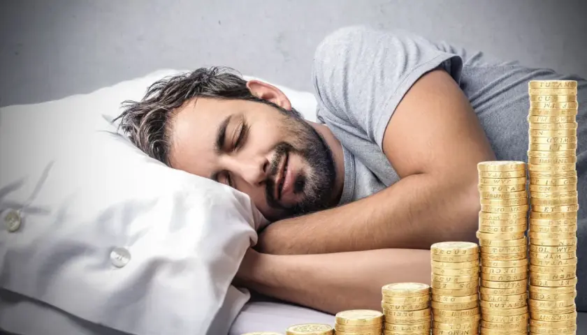 Man sover lugnt bredvid en växande stapel mynt, en dröm om passiva inkomster som blir verklighet.