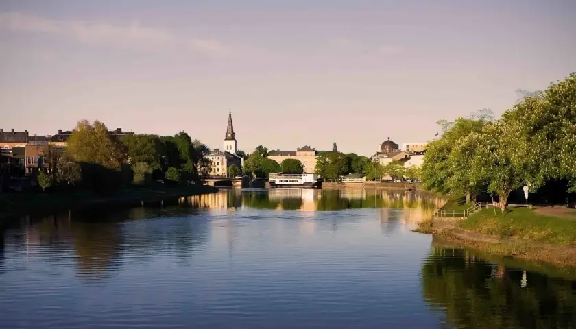 Vacker vy över Klarälven i Karlstad med stadens silhuett, kyrktorn och grönska. Perfekt för gratis aktiviteter Karlstad.