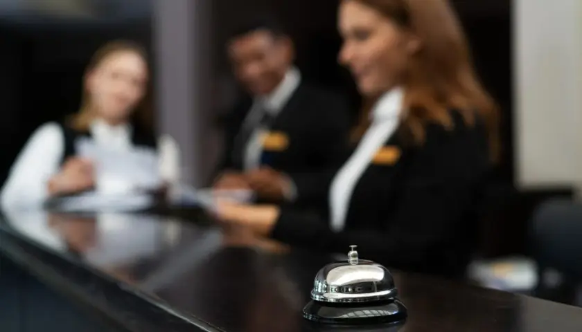 Receptionister i utbildning, redo att hjälpa till. En klocka på disken signalerar service.