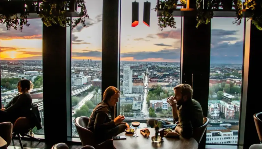Par som njuter av solnedgången över staden från en takbar. En avkopplande aktivitet bland alla **things to do in Lund**.