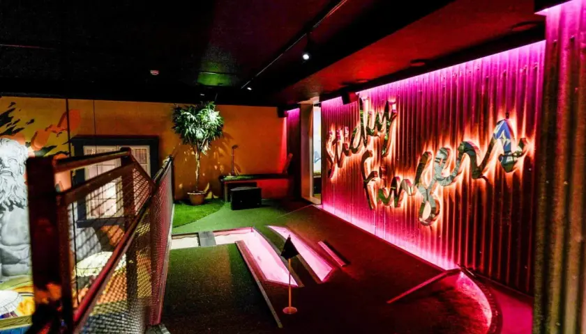 En neonupplyst minigolf bar med en väggtext som säger "Lucky Fun".