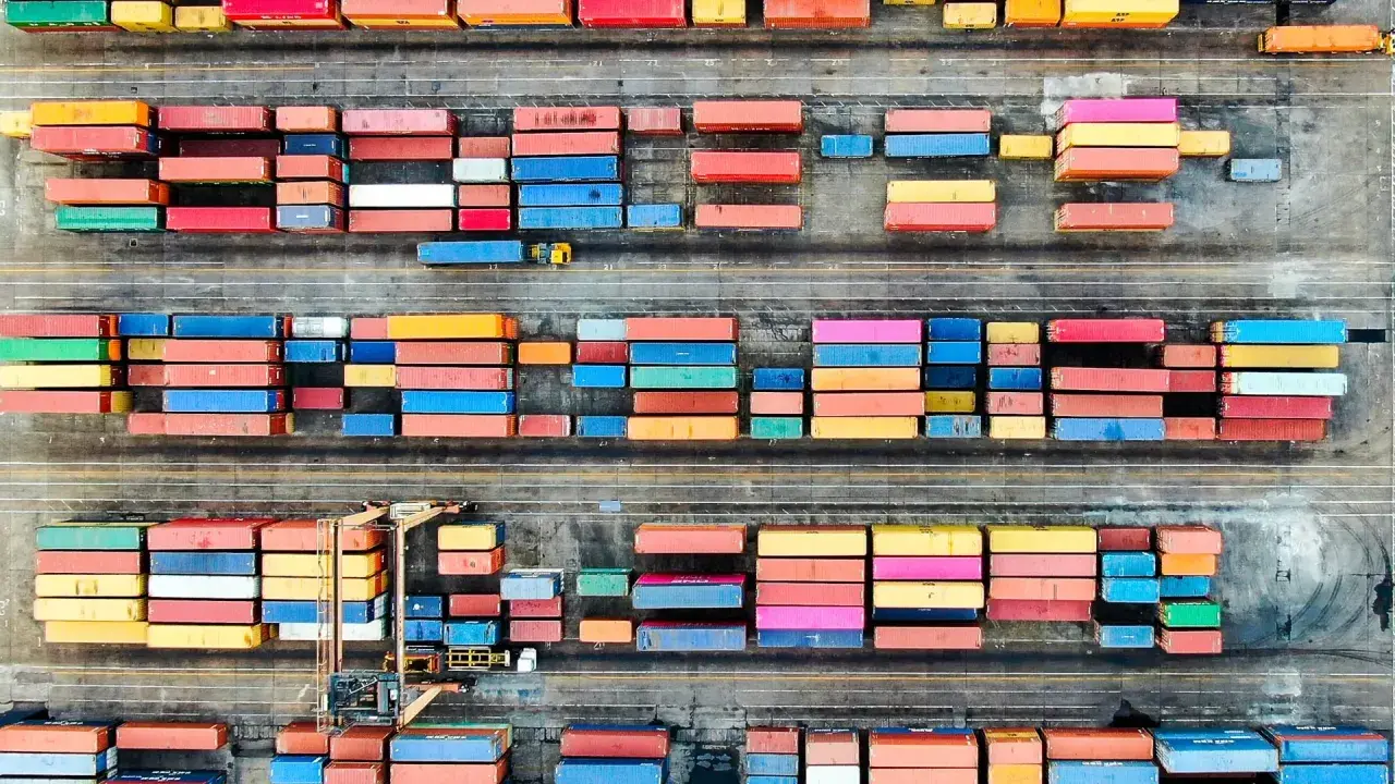 Färgglada containrar staplade på en hamnplan, en symbol för internationell logistik. Chalmers forskar om effektivitet i globala flöden.