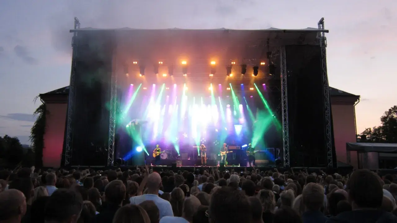 Stor publik njuter av en konsert i Botaniska trädgården. Scenen badar i ljus och rök.