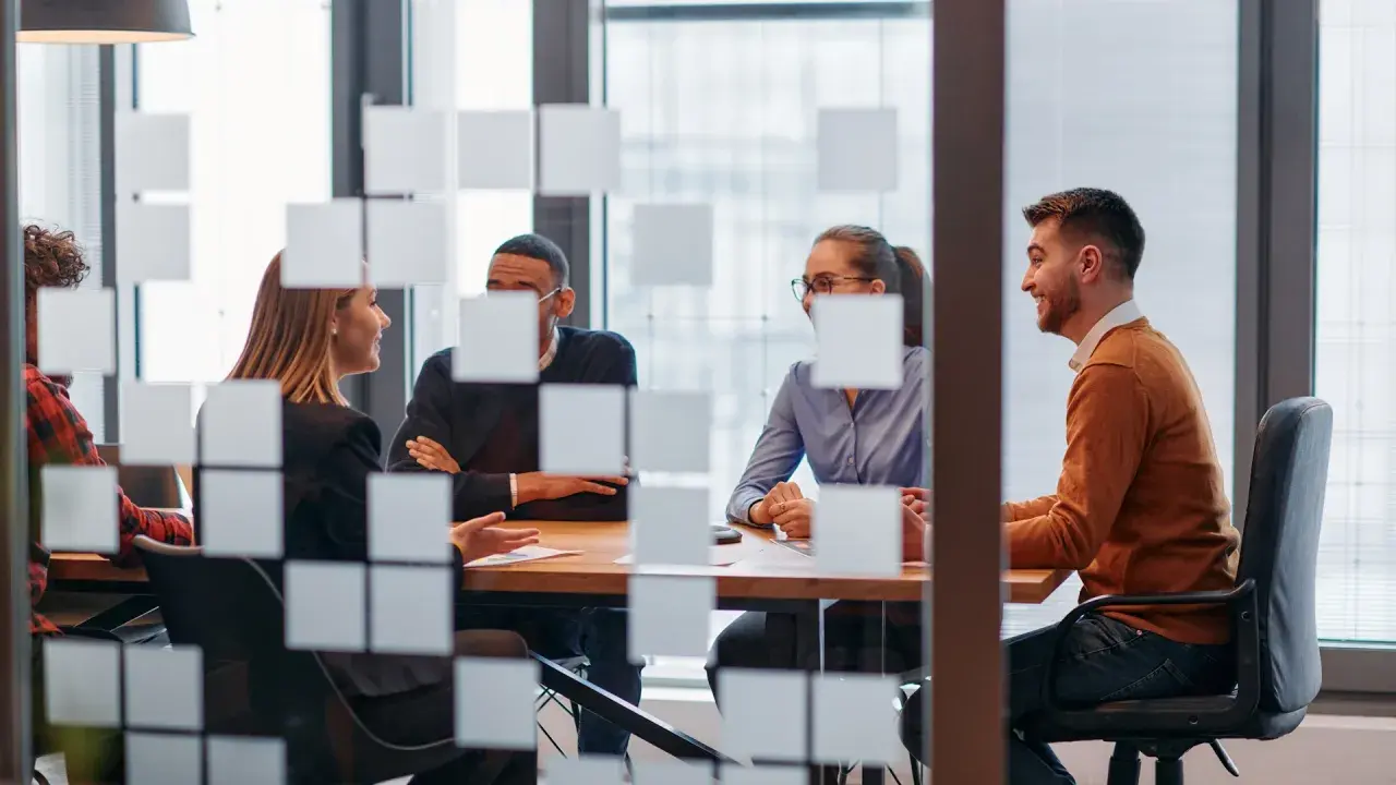 Key account manager diskuterar med kollegor vid ett mötesbord.