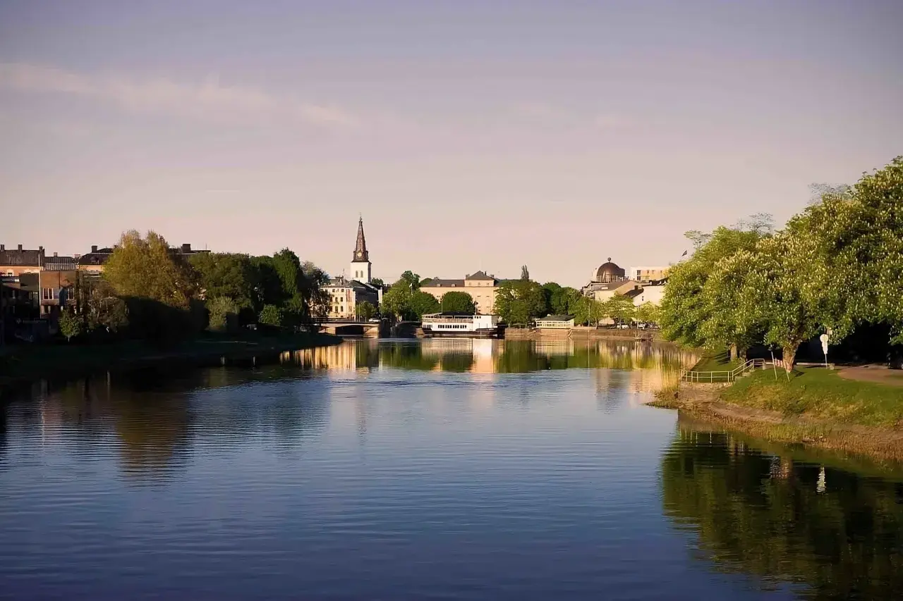 Vacker vy över Klarälven i Karlstad med stadens silhuett, kyrktorn och grönska. Perfekt för gratis aktiviteter Karlstad.
