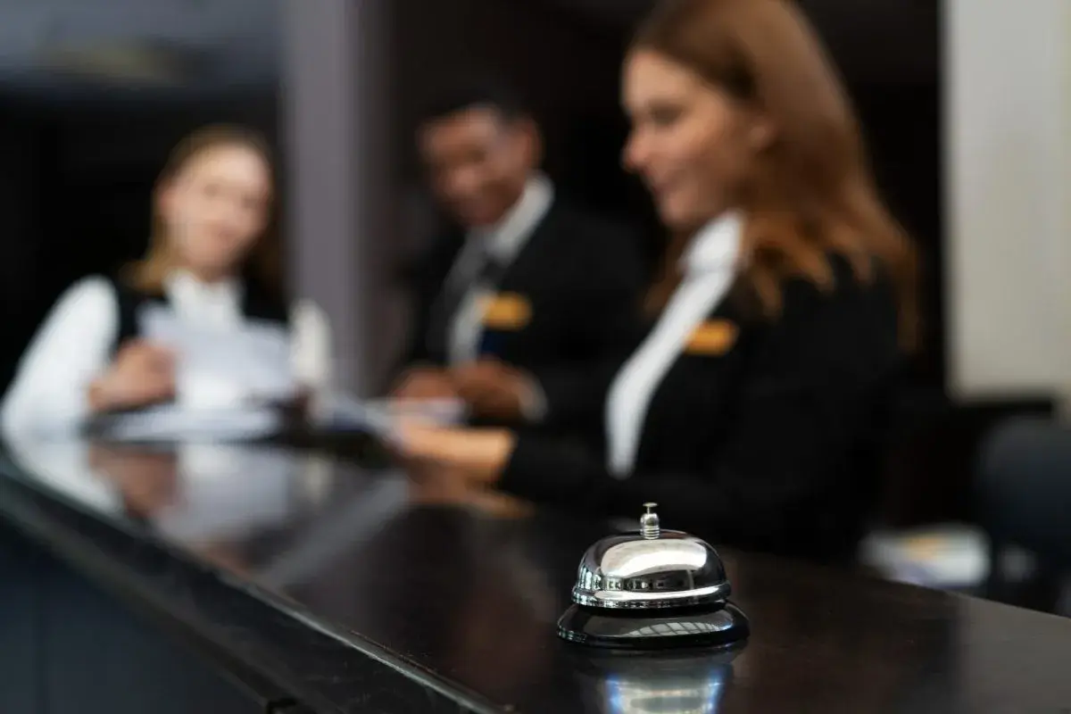 Receptionister i utbildning, redo att hjälpa till. En klocka på disken signalerar service.