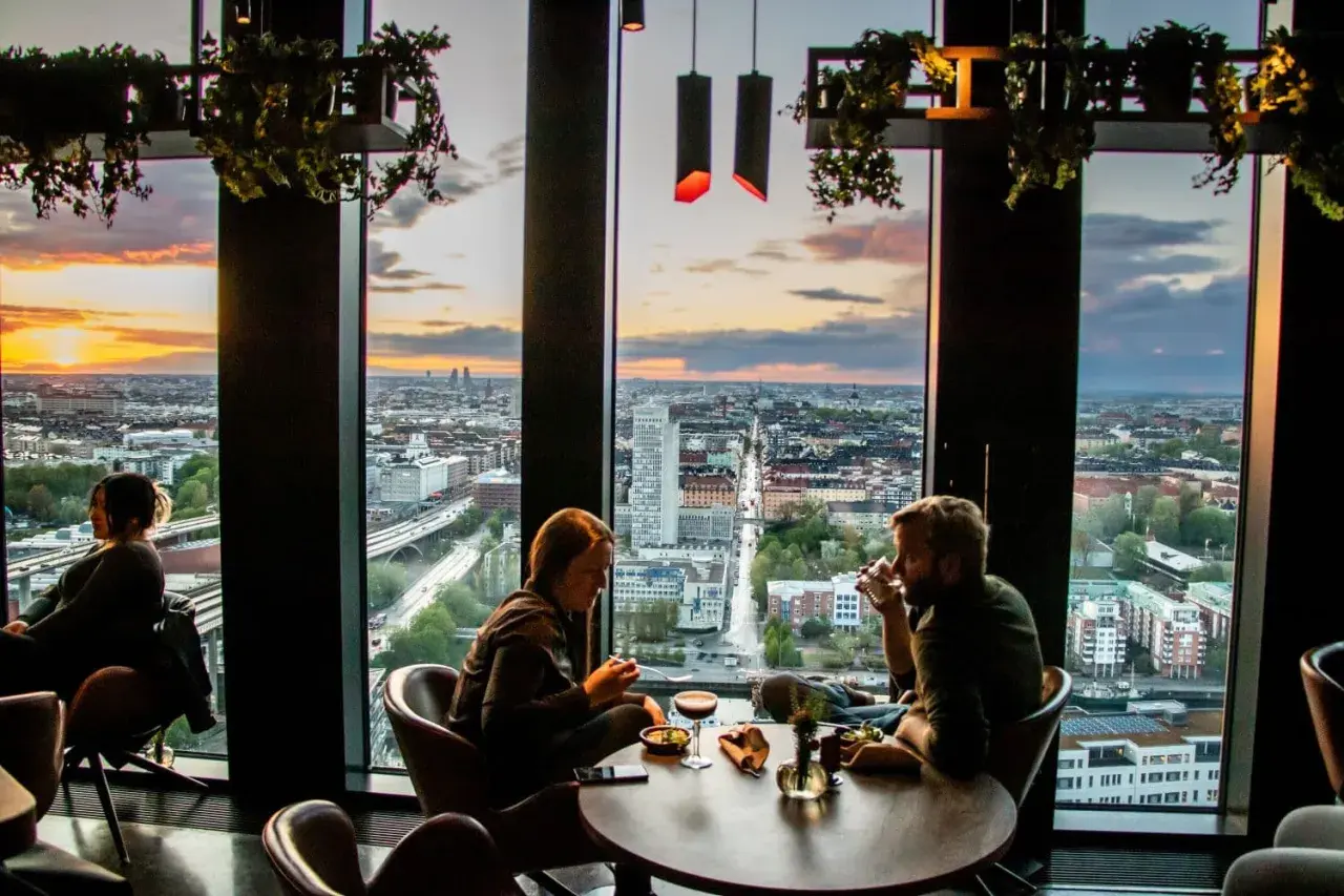 Par som njuter av solnedgången över staden från en takbar. En avkopplande aktivitet bland alla **things to do in Lund**.