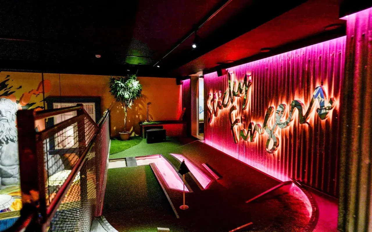 En neonupplyst minigolf bar med en väggtext som säger "Lucky Fun".