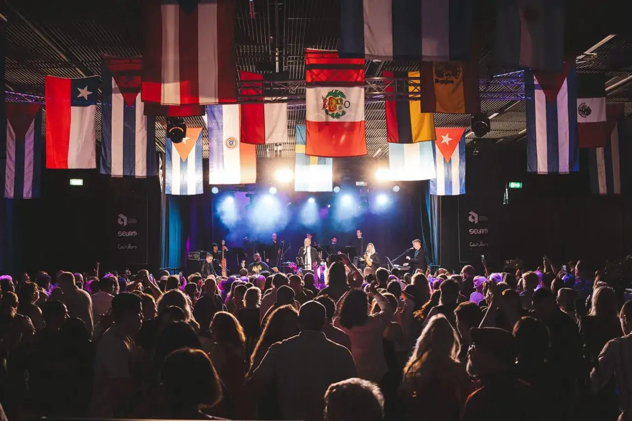 Publik njuter av en konsert i Uppsala, med flaggor från olika länder som hänger från taket.