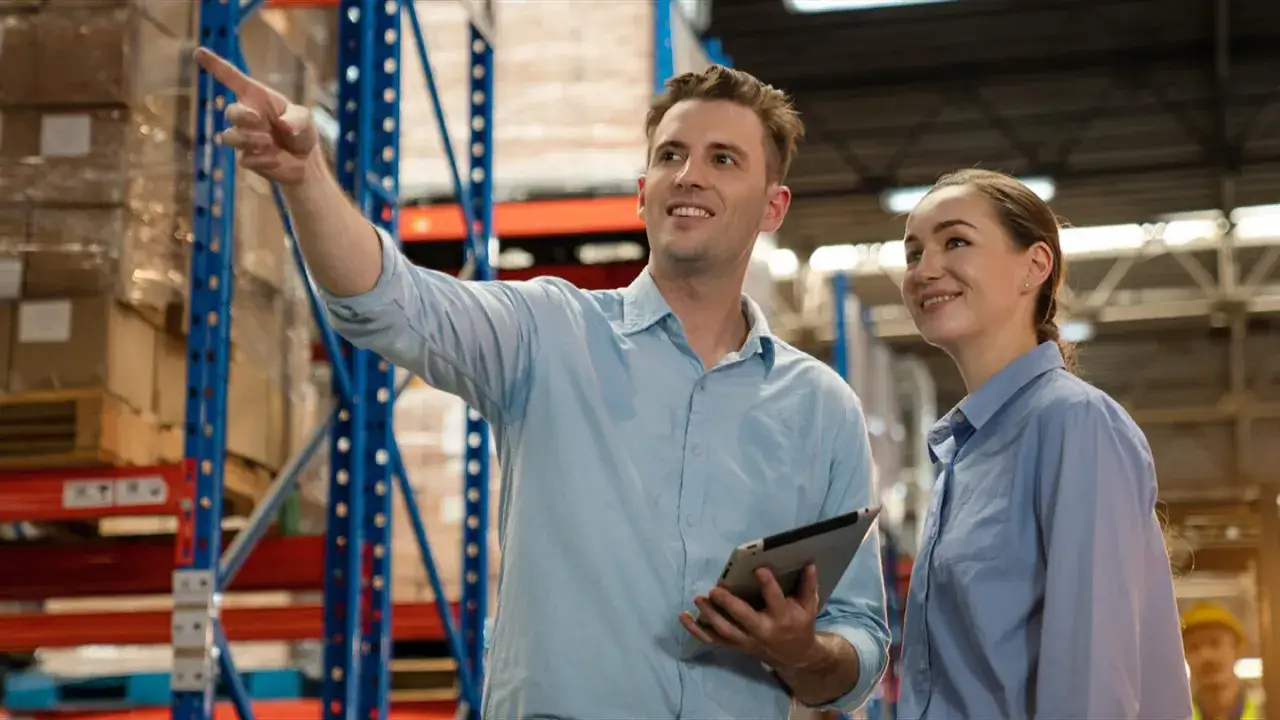 Man pekar och kvinna lyssnar i lager. De diskuterar logistik, som en logistik konsult.
