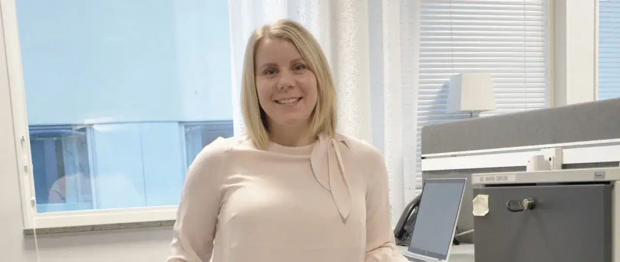 En kvinna ler vid sitt skrivbord, redo att jobba som controller.