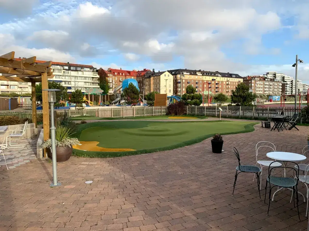 Gr&ouml;nt minigolfomr&aring;de med lekplats i bakgrunden, en del av minigolf Helsingborg.