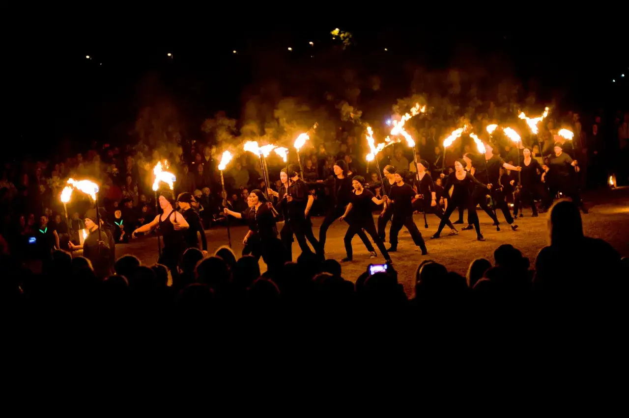 En grupp dansare med facklor lyser upp natten under Uppsala kultur natt. Publiken ser på.