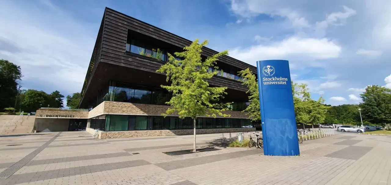 Stockholms universitet med en modern byggnad och en bl&aring; skylt. En lista &ouml;ver universitet i Stockholm kan inkludera detta campus.