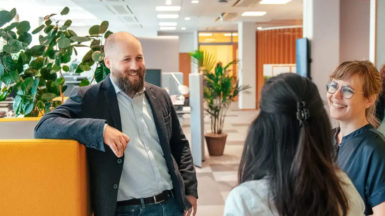 Glada kollegor diskuterar framtiden på ett modernt kontor. Kanske är det dags att söka vinnova lediga jobb?